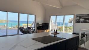 Une cuisine moderne avec de grandes fenêtres, un plan de travail en marbre et une vue sur la mer.