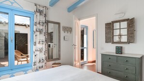 Une chambre à coucher comprenant un lit, une commode, un miroir et une porte donnant sur un balcon.
