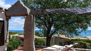 Une arche en pierre, un arbre et une vue sur la mer.