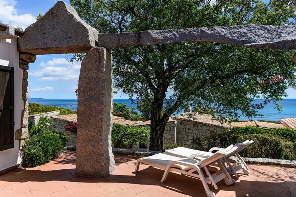 A stone archway, a tree, and a view of the sea.