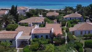 A coastal residential area with terracotta-tiled houses, a beach, and palm trees. - Villa 'Salvi' with Private Terrace, Wi-Fi and Air Conditioning (Costa Rei)