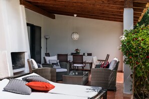 Un patio con mobiliario de mimbre, una mesa y una lámpara colgante.