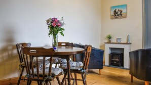 Un coin repas avec une table et des chaises en bois, un vase de fleurs et un tableau accroché au mur.