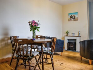Un coin repas avec une table et des chaises en bois, un vase de fleurs et un tableau accroché au mur.