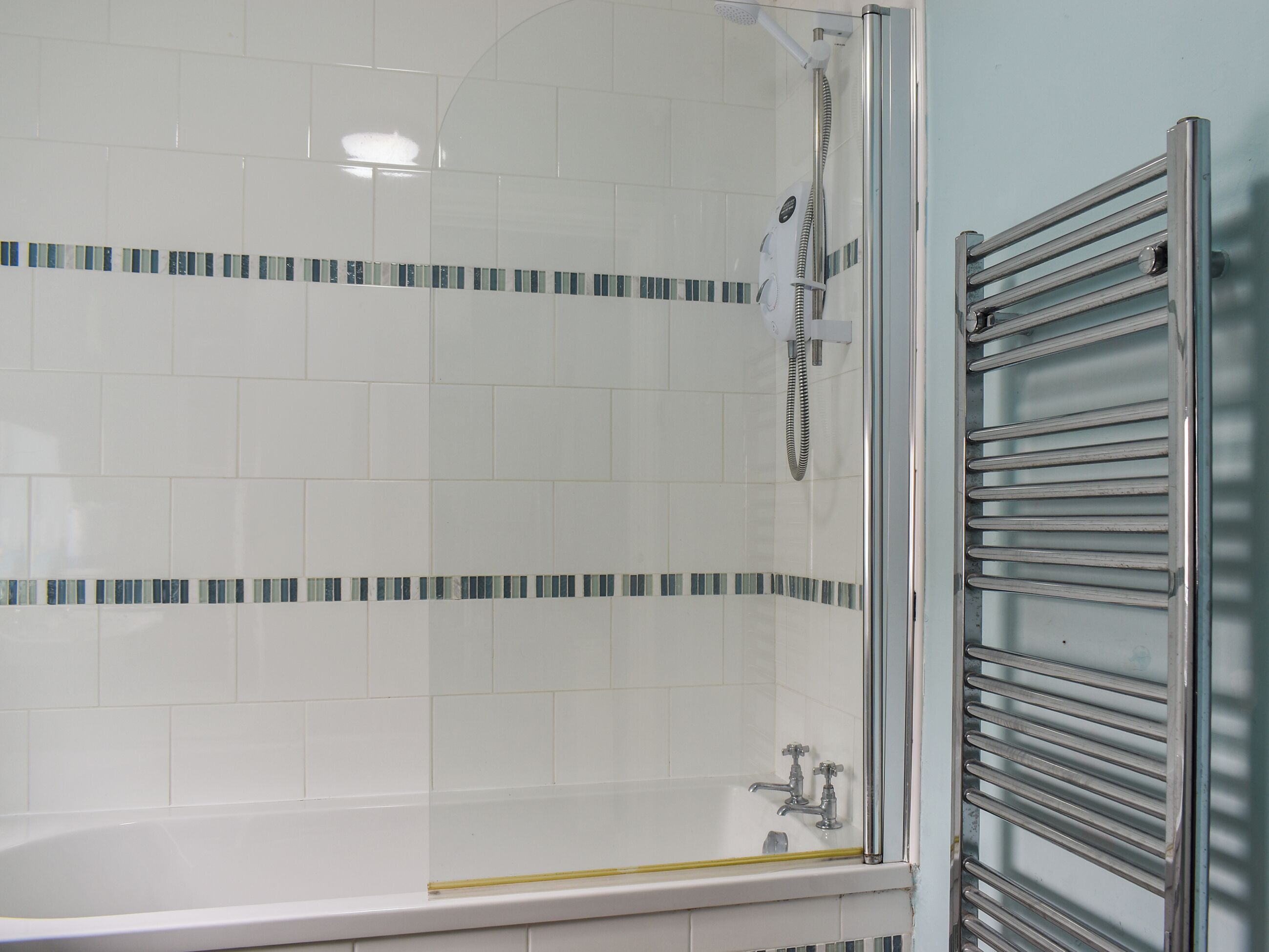 A bathroom with a glass-enclosed shower, a bathtub, and a metal towel rack.