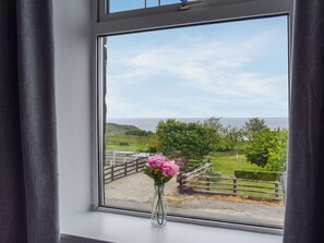 A window with a clear view of a grassy landscape, a wooden fence, and a body of water. - 2 bedroom accommodation in Port Mulgrave, near Whitby (Port Mulgrave, near Whitby)