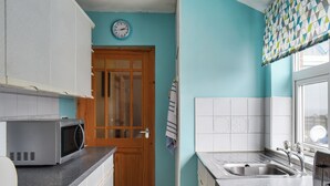 Une cuisine équipée d’un four à micro-ondes, d’un évier et d’une porte en bois.