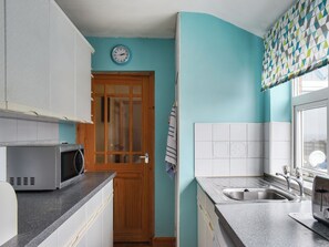 Eine Küche mit Mikrowelle, Spüle und Holztür.