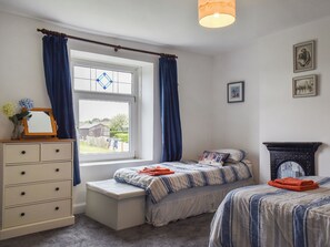 A bedroom with two beds, a dresser, a window with curtains, and a fireplace. - 2 bedroom accommodation in Port Mulgrave, near Whitby (Port Mulgrave, near Whitby)
