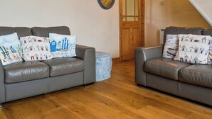 Deux canapés en cuir gris ornés de coussins à motifs, une porte en bois et un miroir au mur.