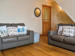 Zwei graue Ledersofas mit gemusterten Kissen, eine Holztür und ein Spiegel an der Wand.