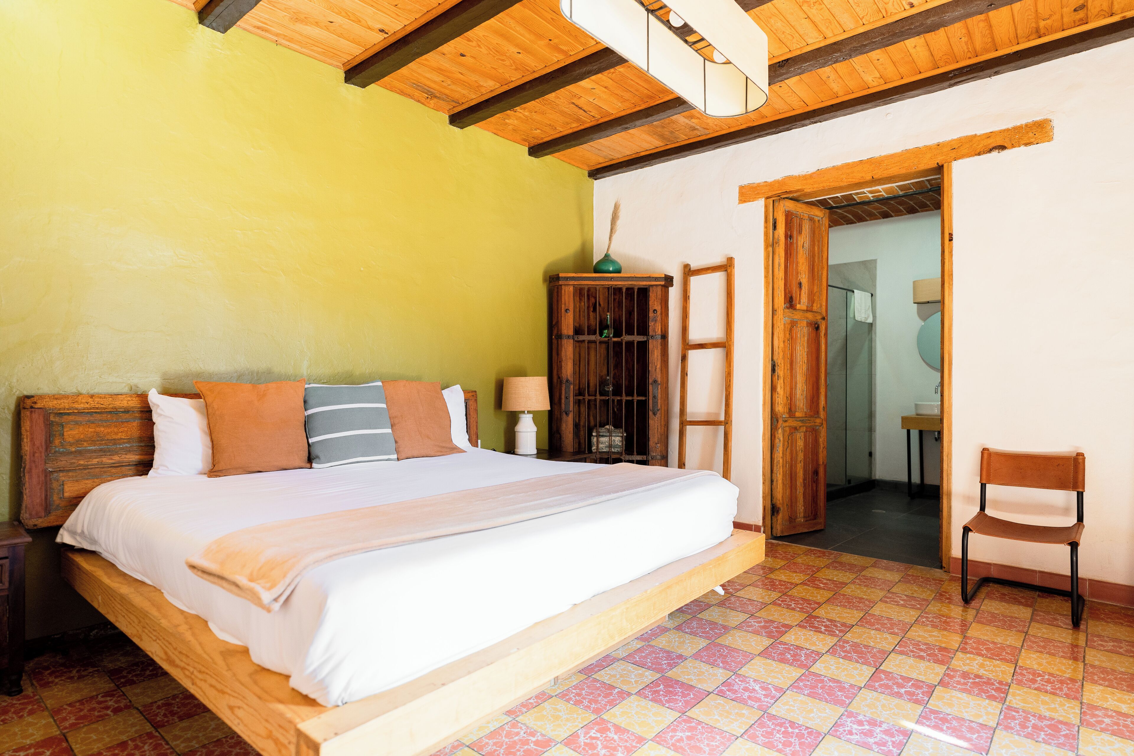 Quarto com cama de madeira, mesa de cabeceira, armário de madeira e uma cadeira.