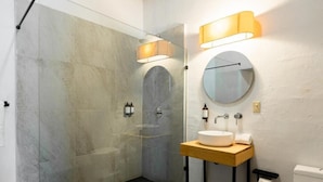 A modern bathroom with a glass shower enclosure, a round mirror, and a wooden vanity. - CASA MADERO (Tapalpa)