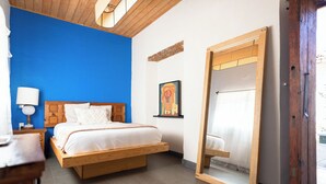 A bedroom with a bed, a nightstand, a mirror, and a blue accent wall. - CASA MADERO (Tapalpa)
