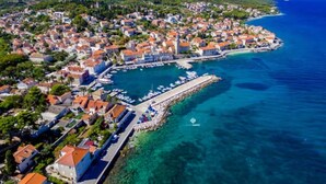 An aerial view of a coastal town with a marina, clear blue waters, and a mix of residential buildings. - Holiday Home House of the Sun (Sutivan)