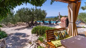 A covered outdoor area with a pool, lounge chairs, and a brick oven. - Holiday Home House of the Sun (Sutivan)