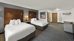 A hotel room with two beds, a desk, a lamp, a picture on the wall, and a coat rack. - Quality Inn & Suites Caribou (Caribou)