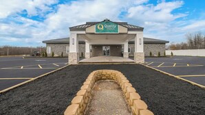 Un hôtel avec une enseigne indiquant « Quality Inn & Suites by Hilton » et un parking situé devant.