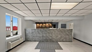 A reception area with a marble counter, a stone wall, a large window, and a tiled floor. - Quality Inn & Suites Caribou (Caribou)