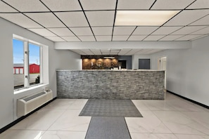 A reception area with a marble counter, a stone wall, a large window, and a tiled floor. - Quality Inn & Suites Caribou (Caribou)