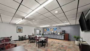 A conference room with a patterned carpet, tables, chairs, a kitchen area, and a TV mounted on the wall. - Quality Inn & Suites Caribou (Caribou)