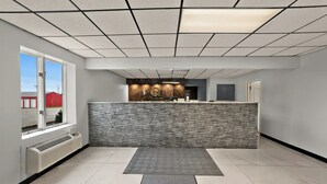 Un espace d’accueil doté d’un comptoir en marbre, d’un mur en pierre, d’une grande fenêtre et d’un sol carrelé.