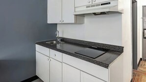 A modern kitchen with white cabinets, a granite countertop, a stainless steel sink, and a built-in oven. - Quality Inn & Suites Caribou (Caribou)