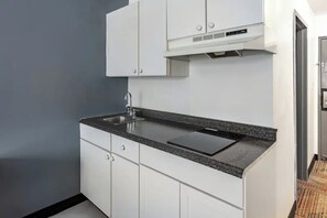 Eine moderne Küche mit weißen Schränken, einer Granit-Arbeitsplatte, einer Edelstahl-Spüle und einem eingebauten Backofen.
