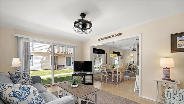 A living room with a TV, sofa, and dining area with chairs and a table.
