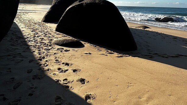 A beach with large rocks and footprints in the sand. - Pouso Trindade (Paraty)