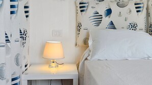 Un dormitorio con cama, una mesita de noche con lámpara y una pared decorada con estrellas.