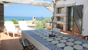 Una terraza con mesa, sillas y vista al mar.
