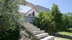 Una escalera de piedra que conduce a un edificio con fachada de piedra y barandilla de metal.