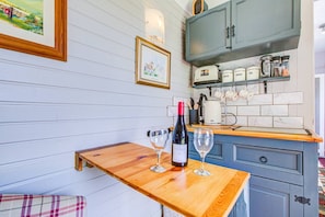 Enjoy cooking in this kitchen with a wine bottle and glasses, a kettle, and a blue cabinet above the countertop.