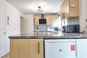 Enjoy cooking in this well-equipped kitchen with a microwave, dishwasher, and tiled backsplash.