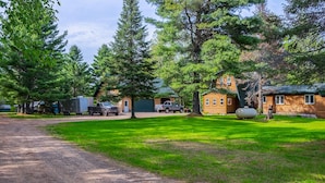 A campground with wooden cabins, a gravel road, and surrounding trees.