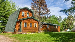 A log cabin with a steeply pitched roof, a front porch, and a well-maintained lawn.