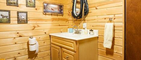 A wooden cabin bathroom with a toilet, sink, and wooden cabinets.