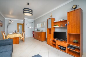 Een moderne woonkamer met een eethoek, een houten entertainmentmeubel en een flatscreen-televisie.