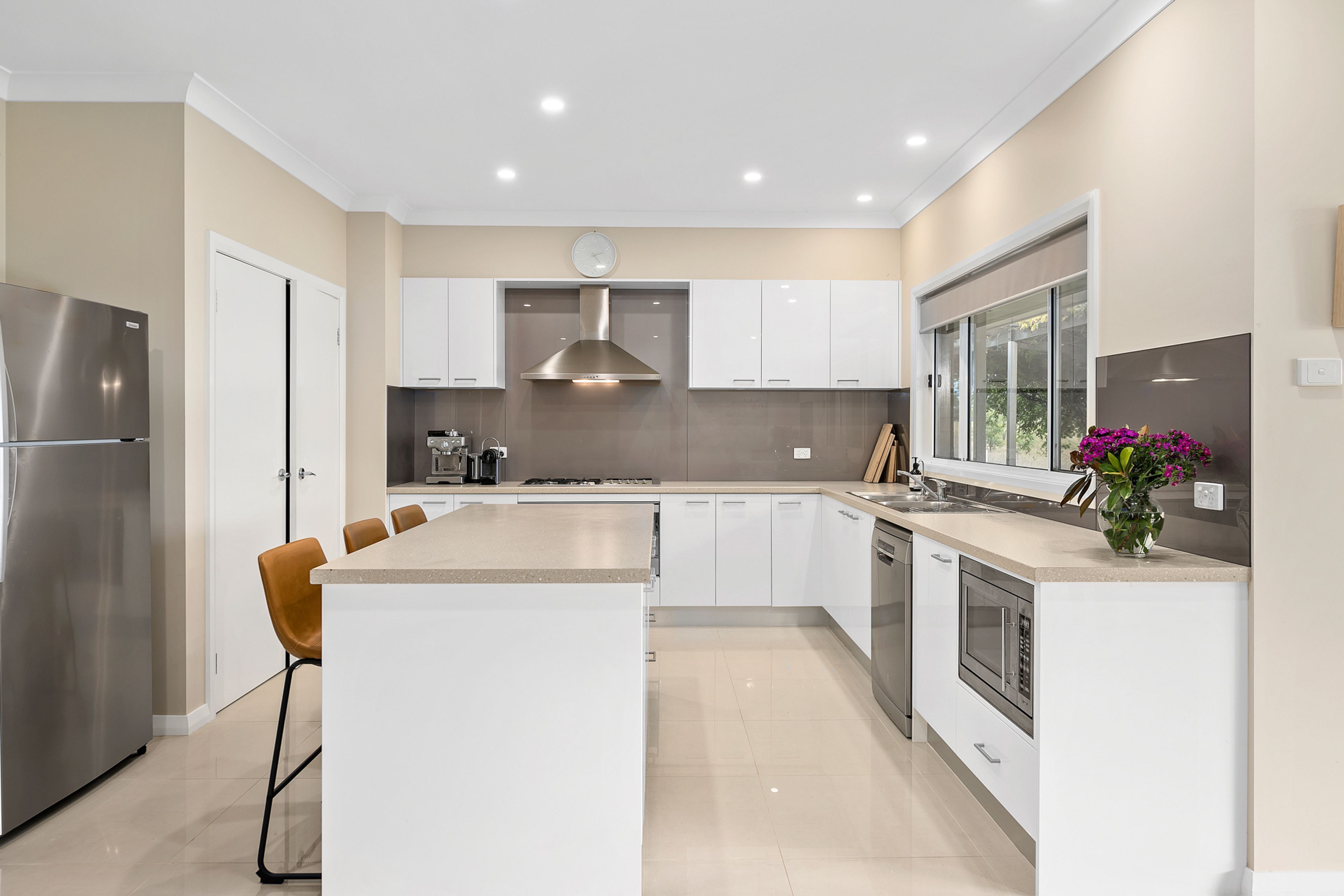 A modern kitchen with a central island, stainless steel appliances, and a large window.