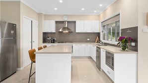 A modern kitchen with a central island, stainless steel appliances, and a large window. - Mole Hill Farmhouse (Keinbah)