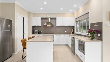 A modern kitchen with a central island, stainless steel appliances, and a large window.