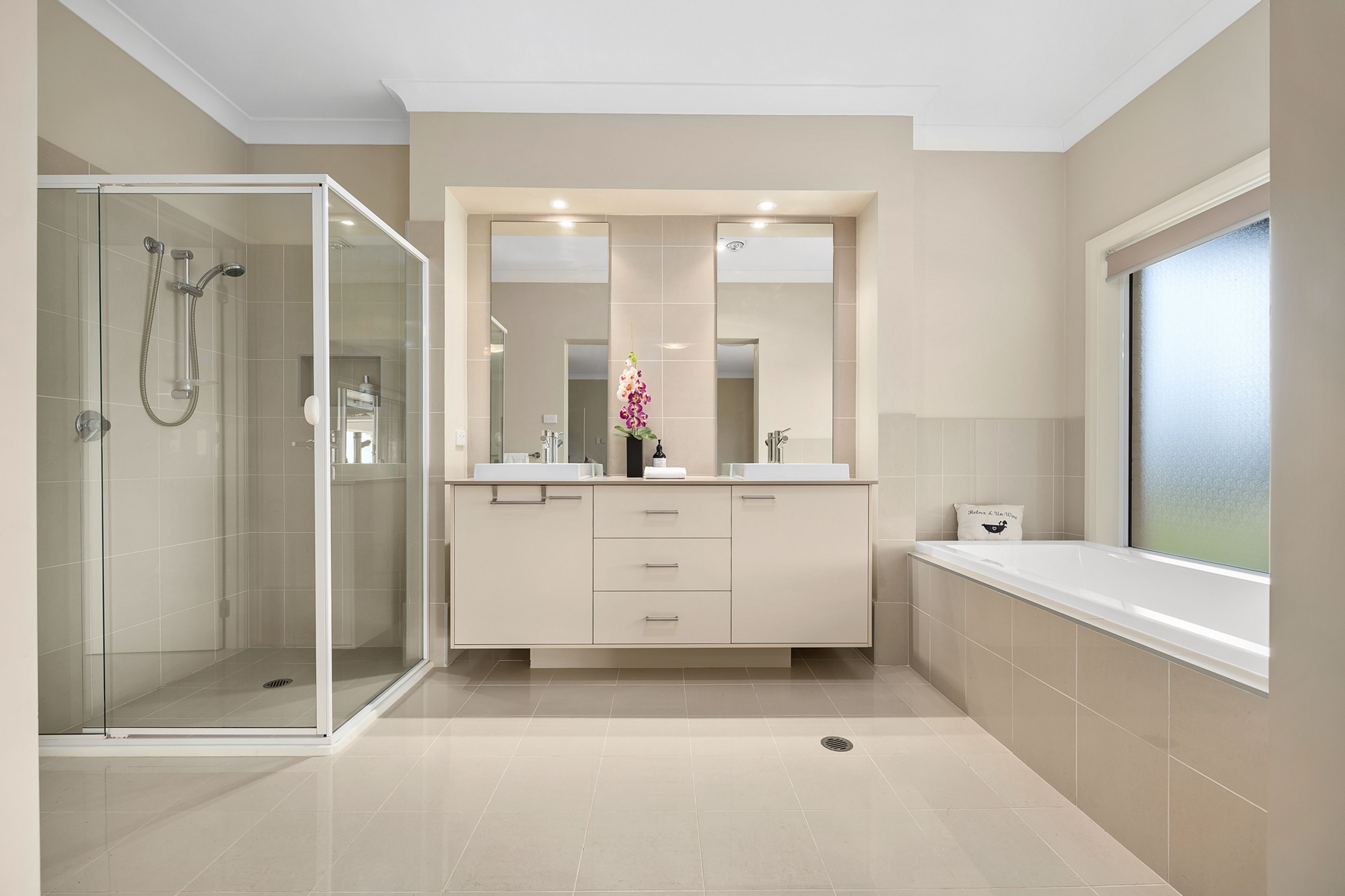 Un baño moderno con ducha envuelta en vidrio, tocador con espejo y bañera.