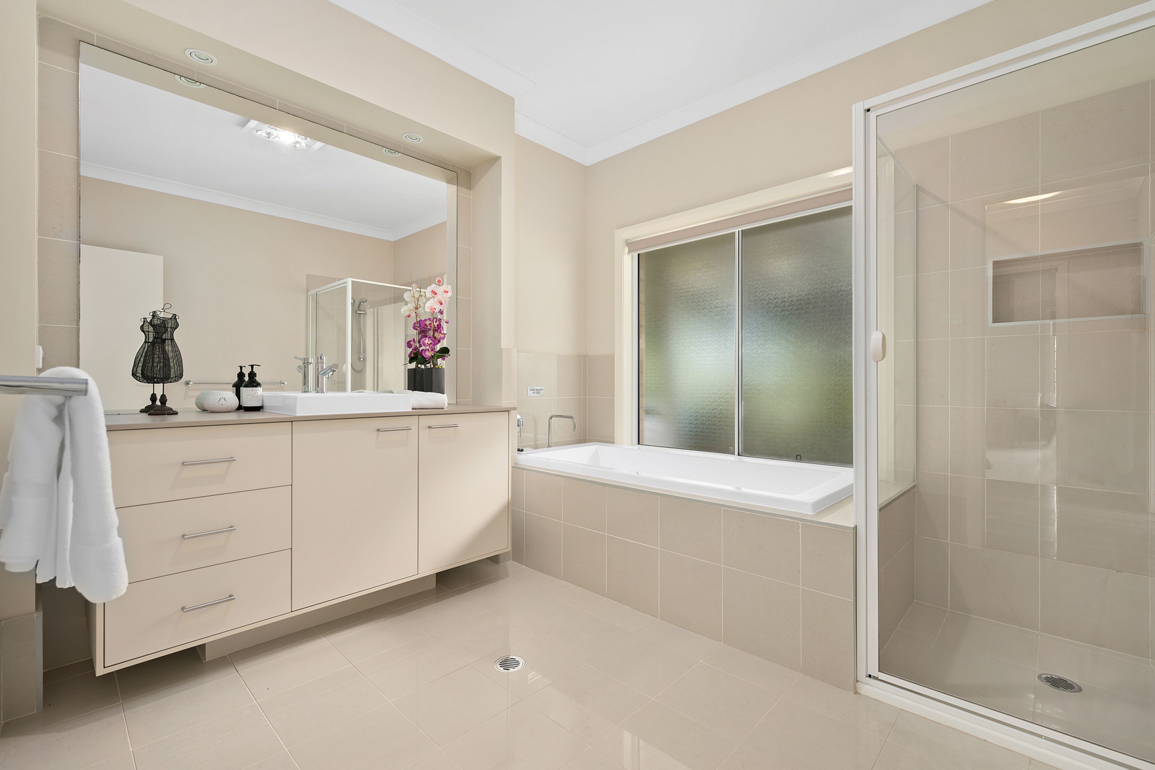 Un baño moderno con un espejo grande, cabina de ducha y tocador con lavabo y espacio de almacenamiento.