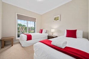Une chambre d’hôtel avec deux lits, une table de chevet, une commode, une fenêtre donnant sur un beau paysage et un tableau au mur.