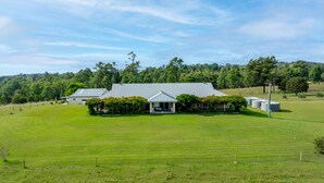 A large, single-story building with a flat roof, surrounded by a well-maintained grassy field. - Mole Hill Farmhouse (Keinbah)