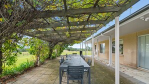 An outdoor patio with a table and chairs, surrounded by a wooden pergola and greenery. - Mole Hill Farmhouse (Keinbah)
