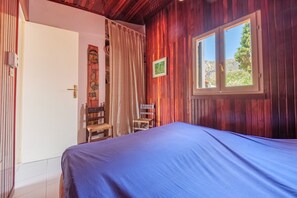 Una habitación con cama, ventana, puerta y una silla.