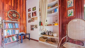 A room with a wooden wall, a bookshelf, a wicker chair, and shelves with various items. - Villa 'Anna Maria' with Sea View, Private Terrace and Wi-Fi (Vulcano)