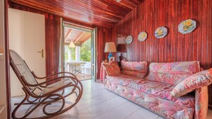 A room with a wooden ceiling, a rocking chair, a patterned sofa, and a table with a lamp. - Villa 'Anna Maria' with Sea View, Private Terrace and Wi-Fi (Vulcano)